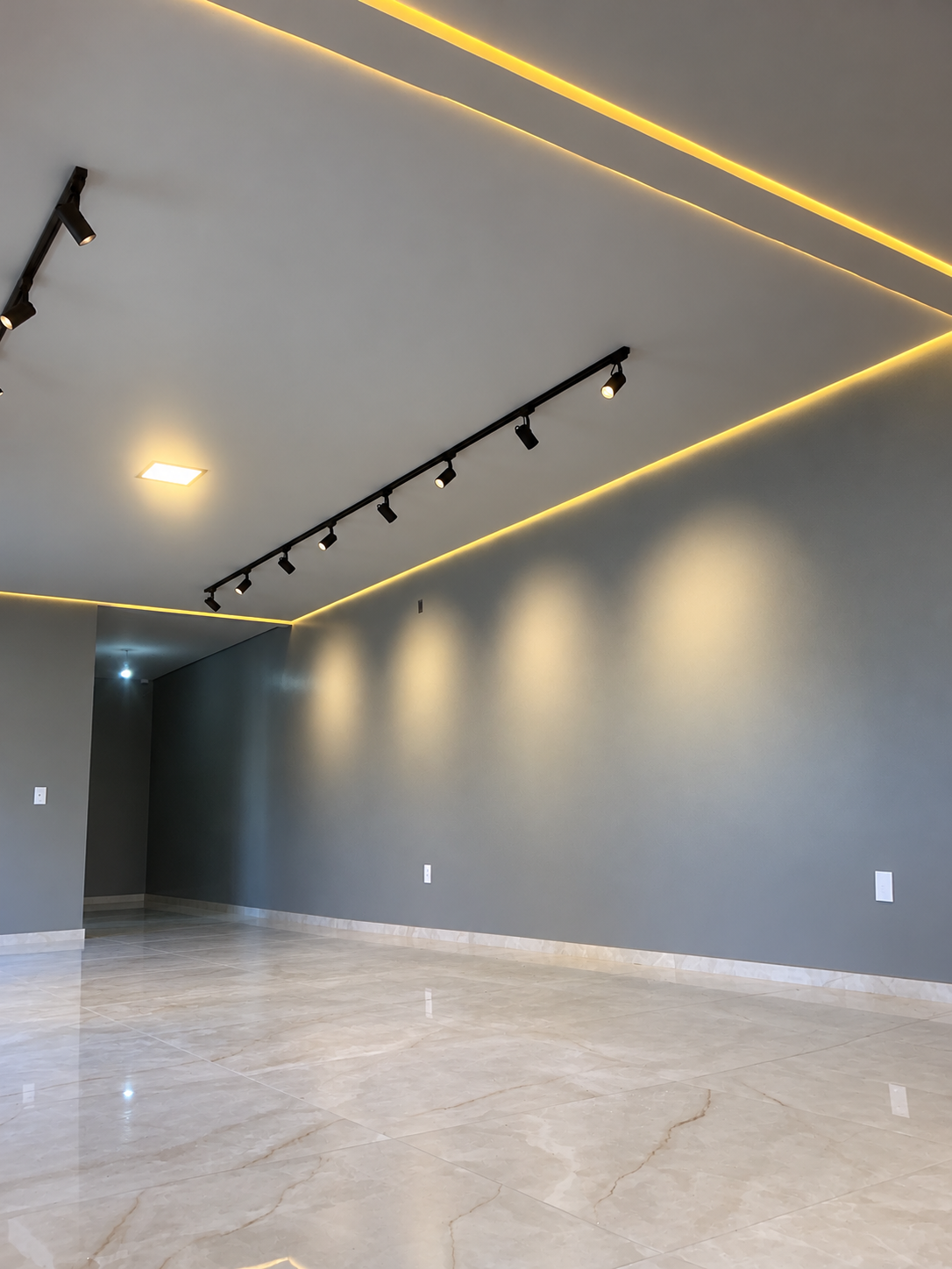 Ambiente da TM Soluções com trilhos pretos, spots direcionáveis e iluminação indireta em LED no teto